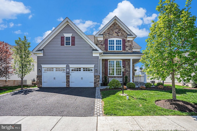 view of front of house with an attached garage, a front lawn, driveway, and stone siding