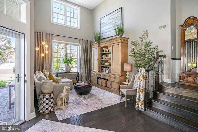 living area featuring visible vents, baseboards, a high ceiling, and dark wood-style floors