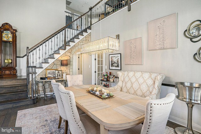 dining room featuring baseboards, a towering ceiling, wood finished floors, and stairway
