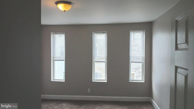 carpeted spare room featuring baseboards