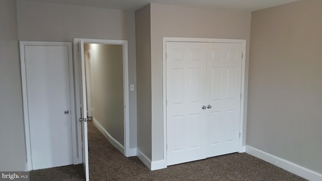 unfurnished bedroom with baseboards, a closet, and dark colored carpet