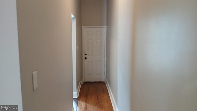 corridor featuring baseboards and wood finished floors