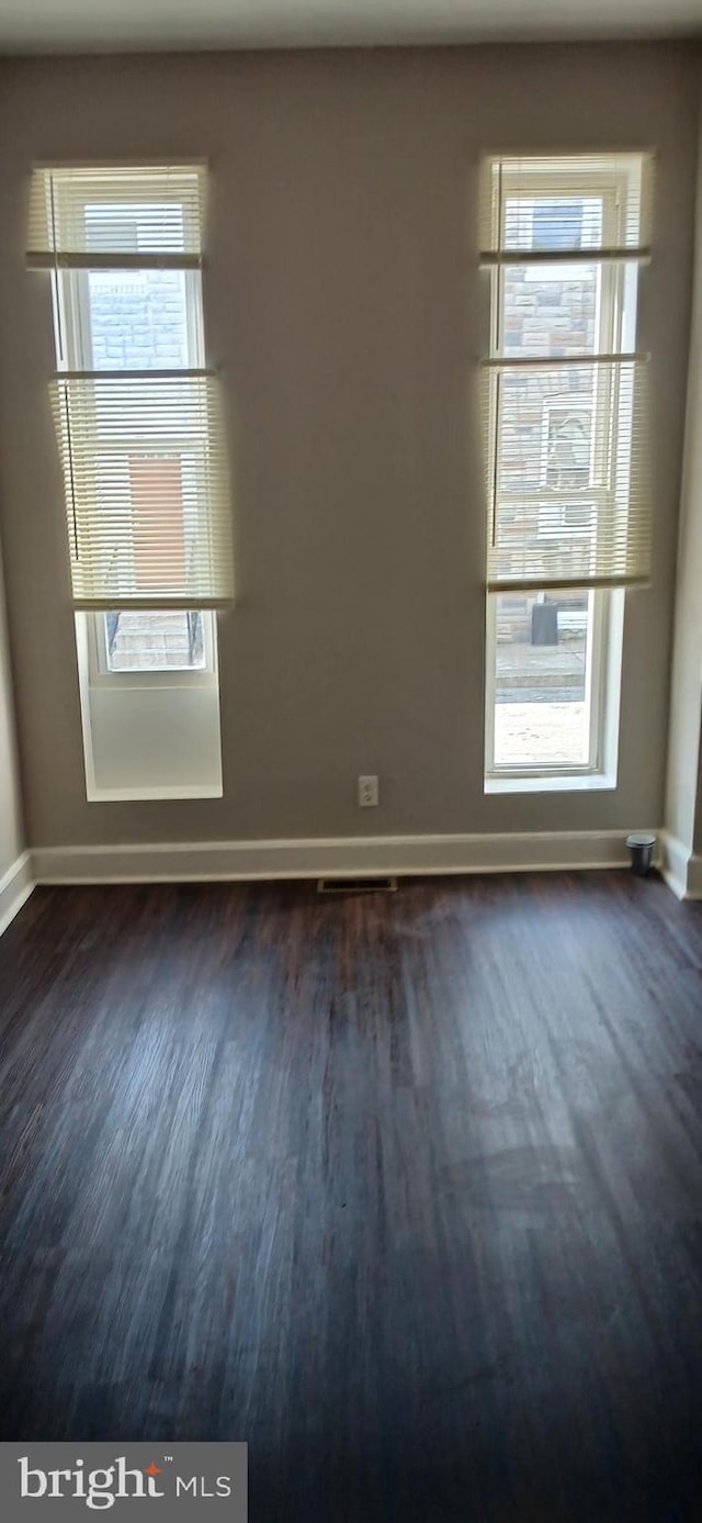 empty room featuring baseboards and dark wood finished floors