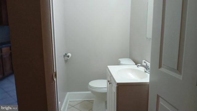 half bathroom with vanity, tile patterned floors, baseboards, and toilet