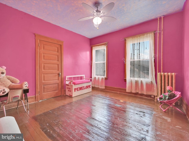 bedroom with wood-type flooring, baseboards, and radiator