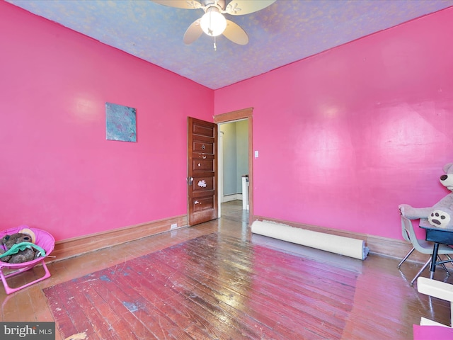 unfurnished room featuring ceiling fan, a baseboard heating unit, baseboards, and hardwood / wood-style flooring