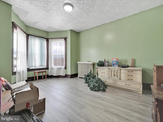 bedroom featuring light wood-style floors, baseboards, and an ornate ceiling