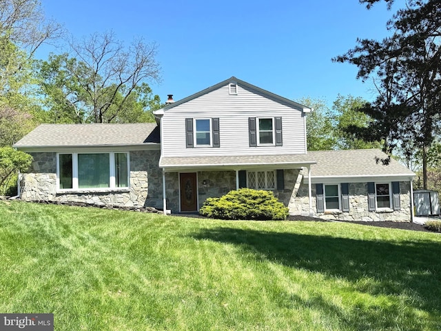 tri-level home featuring a front lawn and stone siding