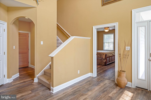 entryway with stairway, arched walkways, baseboards, and wood finished floors