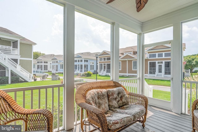 sunroom with a ceiling fan, a healthy amount of sunlight, and a residential view