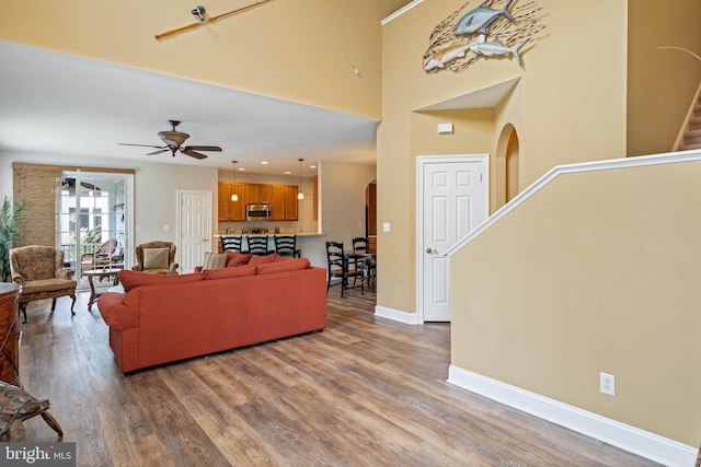 living room featuring baseboards, arched walkways, wood finished floors, and stairway
