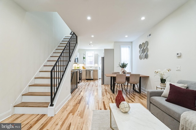 living room featuring visible vents, baseboards, stairway, recessed lighting, and light wood-style flooring