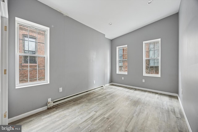 unfurnished room featuring baseboards, a wealth of natural light, wood finished floors, and a baseboard radiator