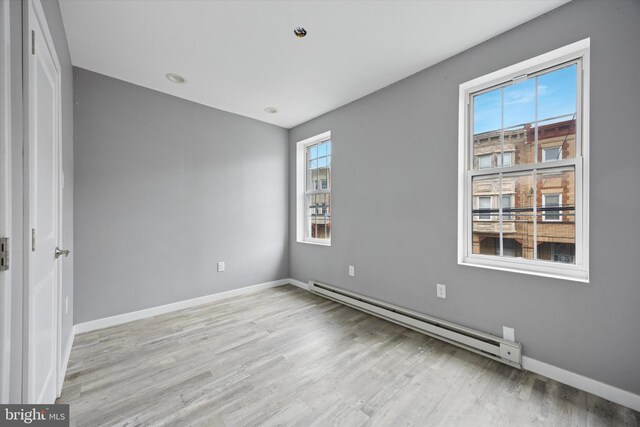 unfurnished bedroom featuring baseboards, light wood-type flooring, and a baseboard radiator