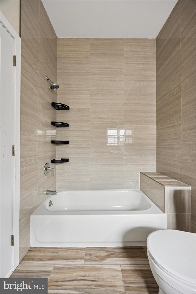 bathroom with tile walls, toilet, and  shower combination