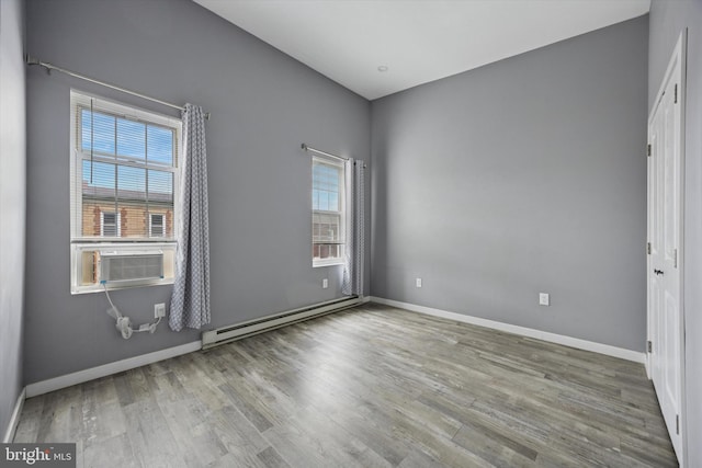 unfurnished room with cooling unit, a wealth of natural light, baseboard heating, and wood finished floors
