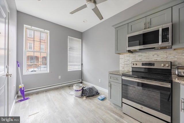 kitchen featuring decorative backsplash, a baseboard radiator, gray cabinets, a ceiling fan, and appliances with stainless steel finishes