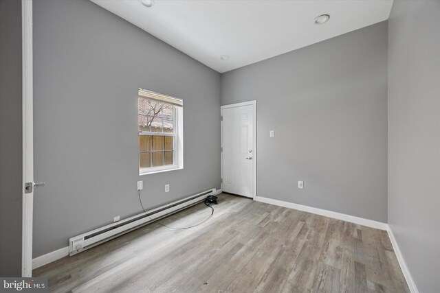 spare room with baseboards, wood finished floors, and baseboard heating