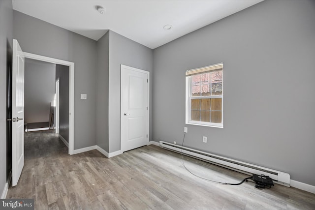 unfurnished bedroom featuring baseboards, baseboard heating, and wood finished floors