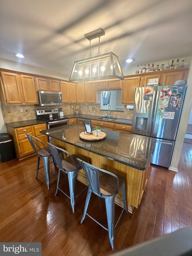 kitchen with a sink, a breakfast bar area, stainless steel appliances, and dark wood-style flooring