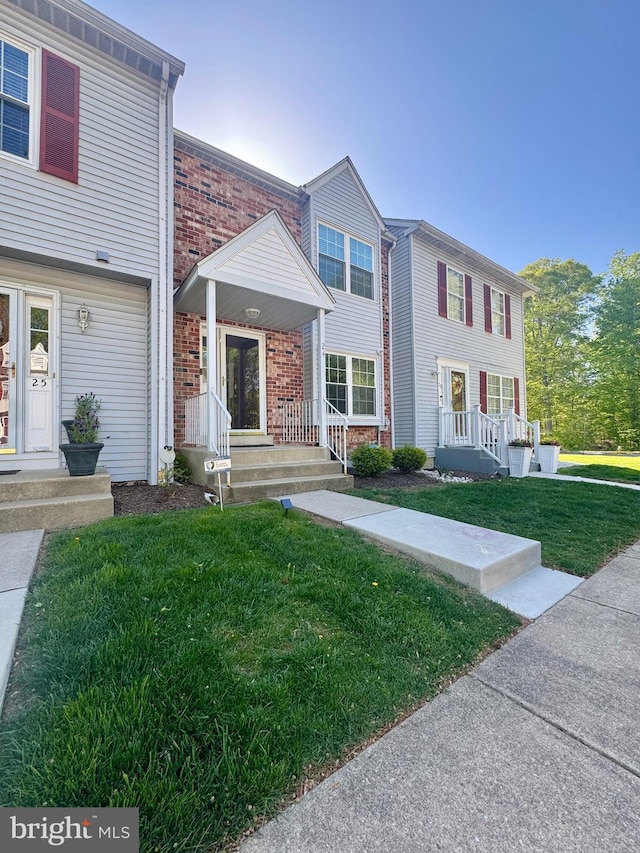 view of property featuring brick siding and a front yard