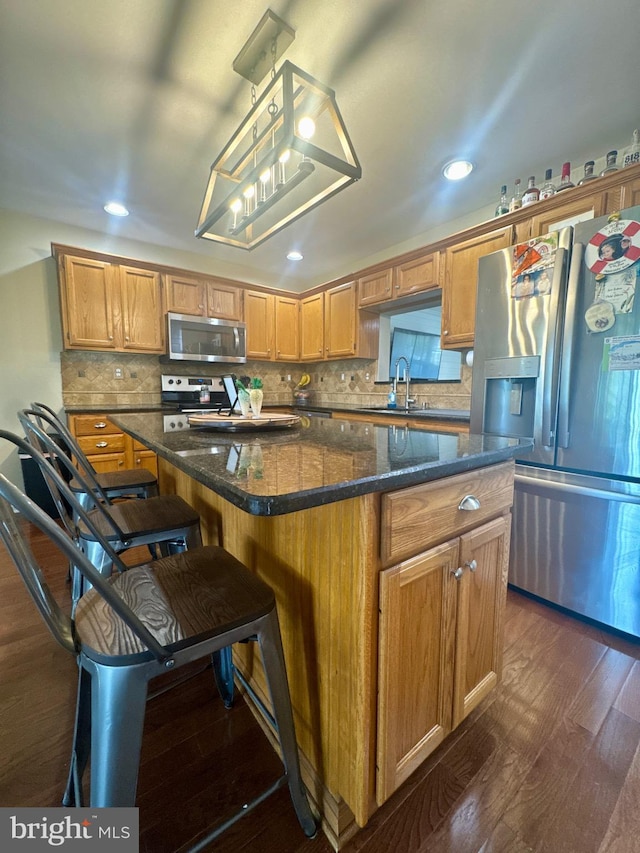 kitchen featuring dark wood-style flooring, a sink, a center island, stainless steel appliances, and recessed lighting