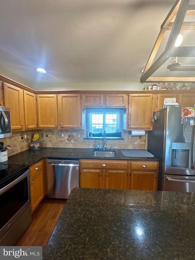 kitchen featuring dark wood-type flooring, a sink, appliances with stainless steel finishes, and backsplash