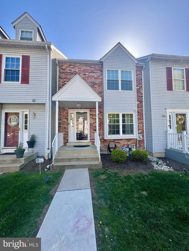 multi unit property with a front lawn and brick siding