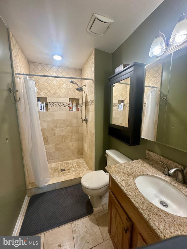 full bathroom featuring vanity, a tile shower, and toilet