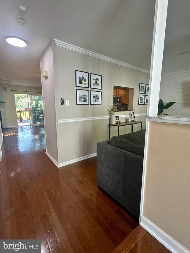 living room featuring crown molding, baseboards, a brick fireplace, and dark wood-style floors