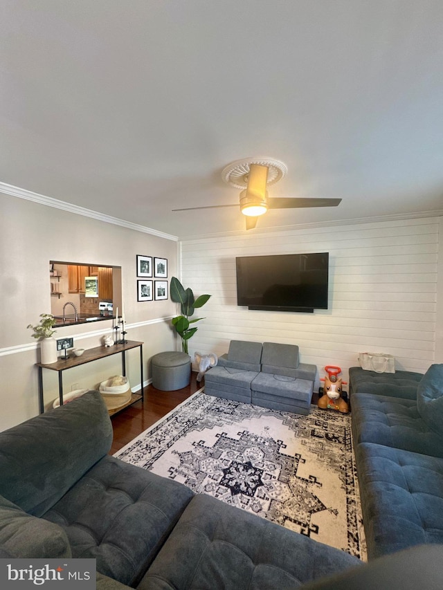 living area featuring crown molding, a ceiling fan, and wood finished floors