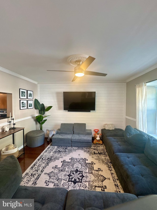 living area with ceiling fan, baseboards, ornamental molding, and wood finished floors