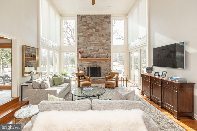living area with ornamental molding, light wood-style flooring, and a towering ceiling