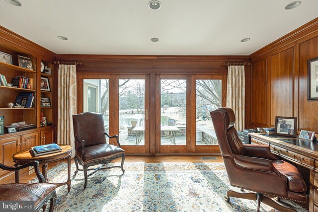 office area featuring crown molding, built in shelves, a healthy amount of sunlight, and wood finished floors