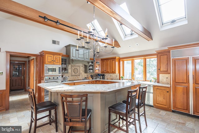 kitchen with a skylight, high vaulted ceiling, stone finish floor, and built in appliances