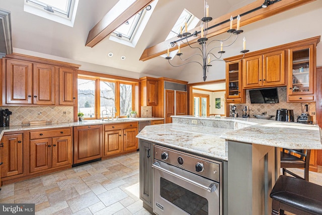 kitchen featuring a towering ceiling, oven, a kitchen bar, brown cabinets, and a skylight