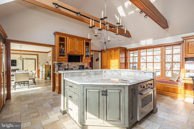 kitchen featuring stone tile flooring, decorative backsplash, stainless steel oven, and a chandelier