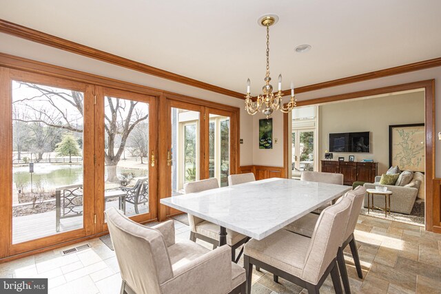 dining room with an inviting chandelier, a wainscoted wall, ornamental molding, and visible vents