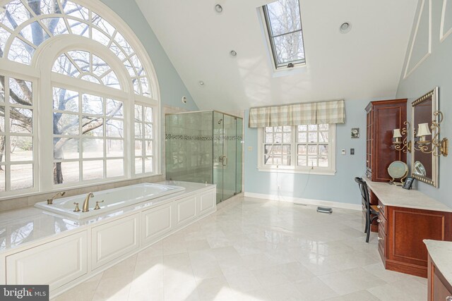 full bath featuring a garden tub, a skylight, a stall shower, high vaulted ceiling, and baseboards