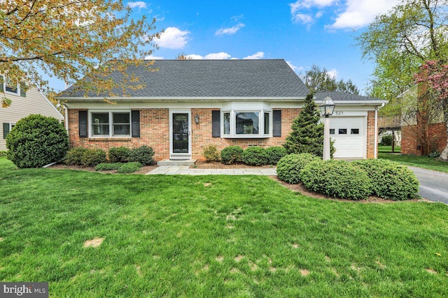 view of front of home with a shingled roof, an attached garage, a front lawn, and brick siding
