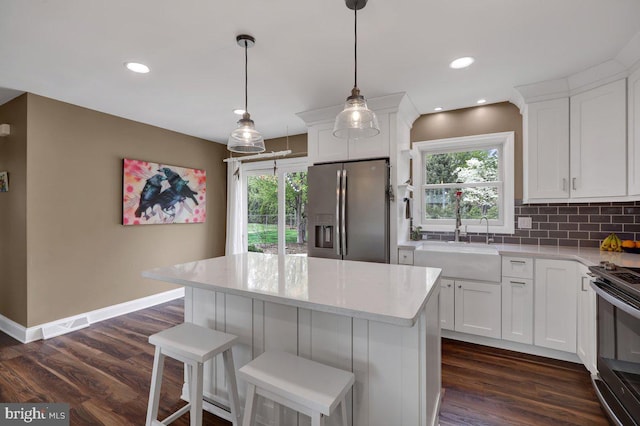 kitchen with a sink, decorative backsplash, white cabinets, and stainless steel appliances