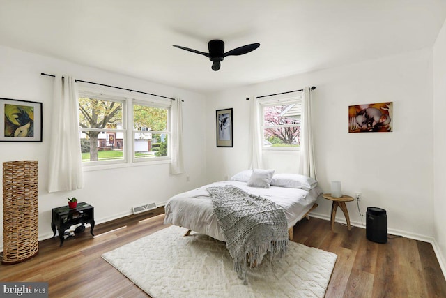 bedroom featuring ceiling fan, baseboards, visible vents, and wood finished floors