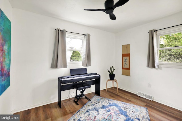 living area featuring visible vents, a ceiling fan, baseboards, and wood finished floors