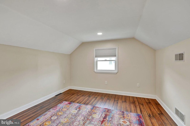 additional living space with visible vents, baseboards, lofted ceiling, and hardwood / wood-style floors