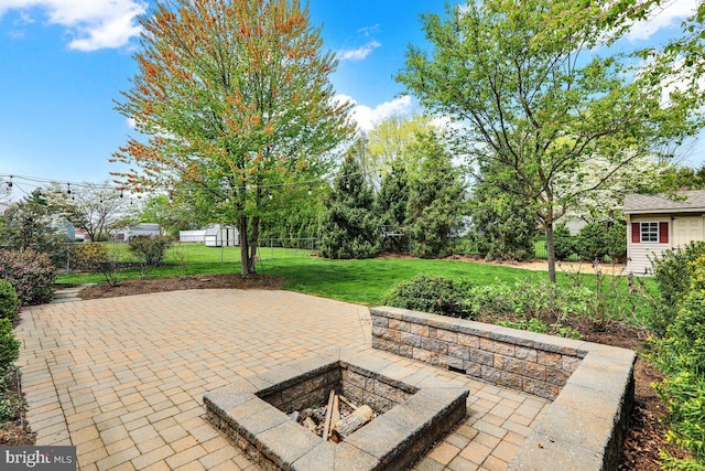 view of patio / terrace featuring an outdoor structure, a fenced backyard, and a fire pit