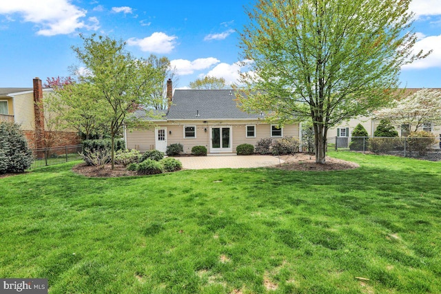 rear view of house with a lawn, fence, a chimney, and a patio area