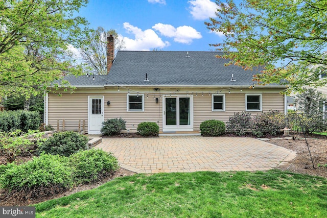 rear view of house with a patio, a yard, and a chimney