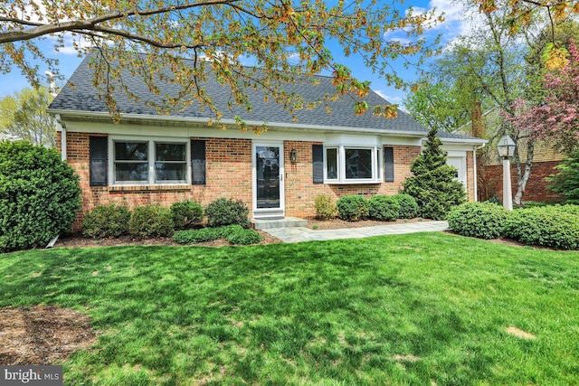 view of front of property featuring a shingled roof, an attached garage, a front lawn, and brick siding