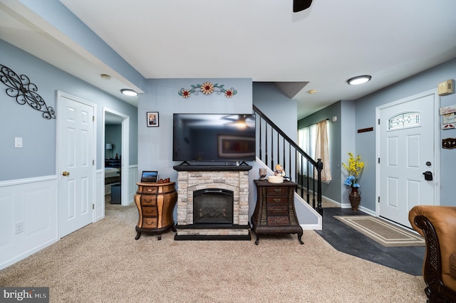 carpeted living area with a fireplace and stairs