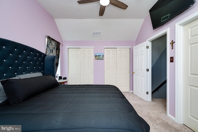 bedroom with visible vents, carpet floors, two closets, and lofted ceiling
